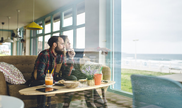 Spain, Asturias, Couple enjoying the seascape through the cafe window while having a brunch