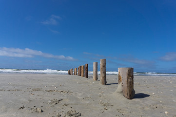 Einsamer Strand mit Holzposten die bis zur Wasserkante führen