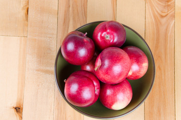 red apples in green bowl on wood floor