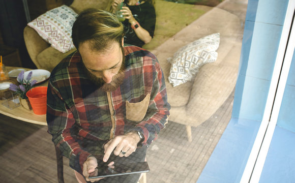 Portrait of bearded man using digital tablet behind in cafe