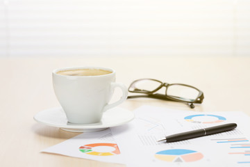 Office workplace with coffee, supplies and reports