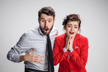The surprised business man and woman on a gray background