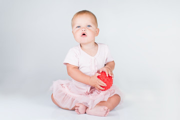 Happy little girl in a short pink dress throws a big striped ball