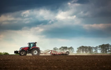Crédence de cuisine en verre imprimé Tracteur Tracteur agricole labourant et pulvérisant sur le terrain