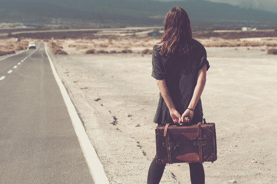 Young woman with suitcase walking on a road