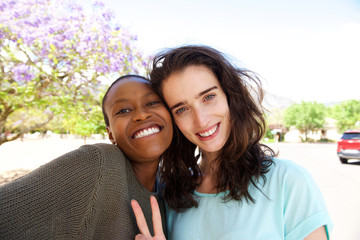 Two beautiful female friends smiling outside