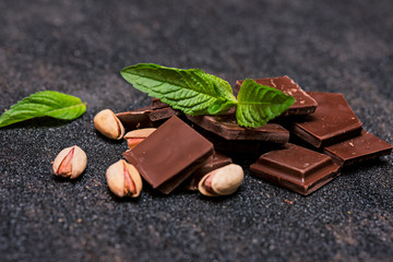 pieces of chocolate with mint and nuts on a dark table