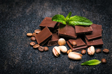 pieces of chocolate with mint and nuts on a dark table