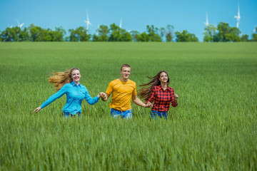 Obraz premium Young happy Friends running on green wheat field