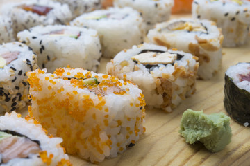 Different Sushi rolls,wasabi and ginger on a plate on wooden bac