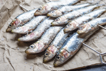 fresh sardines raw fish with coarse salt and thyme on brown pape