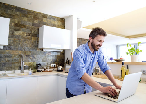 Man working in kitchen using laptop