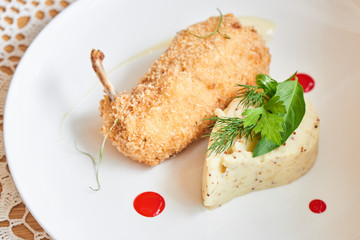 Chicken Kiev fried in breadcrumbs, Parmesan sauce and mashed potatoes with Dijon mustard served on white plate closeup