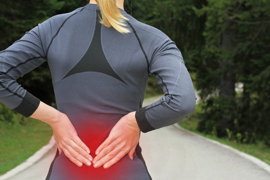 Back Pain. Athletic Fitness Woman Rubbing The Muscles Of Her Lower Back. Sports Exercising Injury.