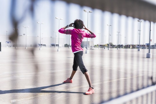 Young woman stretching on parking lot