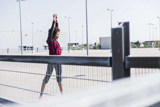 Young woman stretching on parking lot
