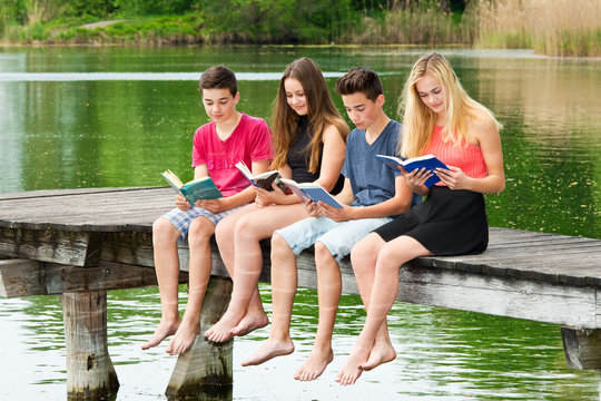 Gruppe Jugendliche lesen draußen ein Buch / Bücher