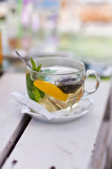 Tea with mint in a transparent mug on white wooden table