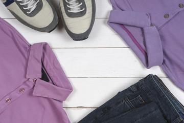 set of men's clothing and shoes on wooden background. Sports T-shirt and sneakers in bright colors. Top view