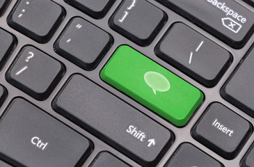 Computer keyboard closeup with chat bubble icon on green enter key