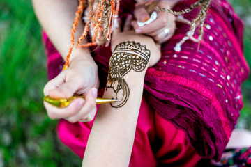 Picture of human hand being decorated with henna tattoo, mehendi