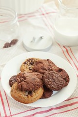 Mix of homemade chocolate chips and cookies with milk over the dining table to take a snack in afternoon.