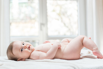 Little naked baby girl lying down
