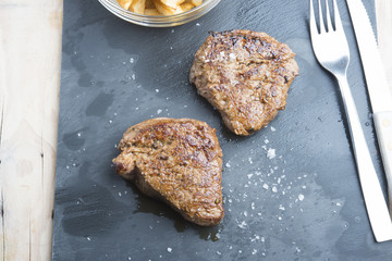 cooked beef chateaubriand steak with chunk chipped potatoes on p