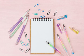 Office set with notebook, colored pens and clips on pink background