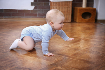 Crawling baby on the wooden floor in the room