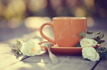 Orange cup with a spoon and a white dogrose