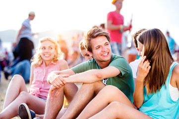 Obraz na płótnie Canvas Teenagers at summer music festival, sitting on the ground