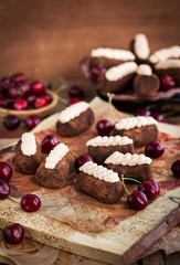 Chocolate rum balls cakes decorated with cream and fresh cherry