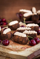 Chocolate rum balls cakes decorated with cream and fresh cherry