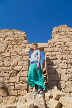 Tourist with turban posing in front of ruined stone house in desert, Egypt.
