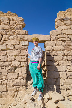 Tourist with turban posing in front of ruined stone house in desert, Egypt.