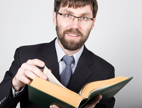 bearded businessman in a business suit and tie, reading a thick book