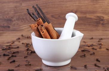 Fragrant cinnamon and vanilla sticks in mortar on rustic board