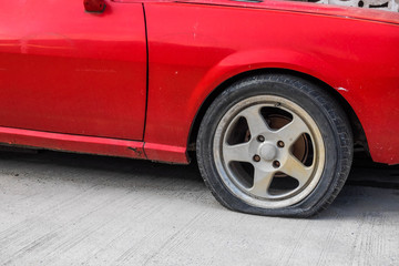 A tire of red old car was puncture
