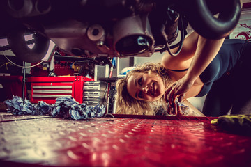 Blond woman repairing motorcycle.