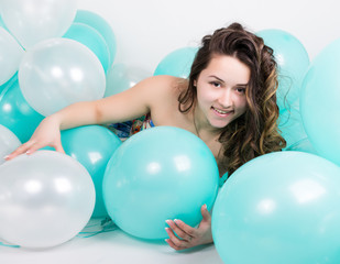Fototapeta na wymiar beautiful curly girl in a multi-colored dress playing with balloons
