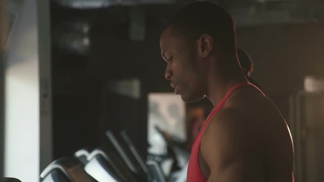 Side view of muscular handsome black man jogging on a treadmill in the gym