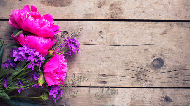 Pink peonies flowers on aged wooden background.