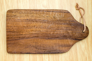 Top view of dark brown wooden chopping block on light wood count