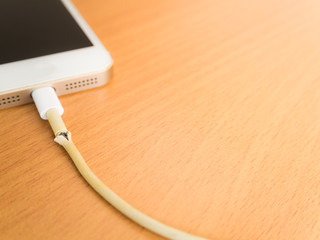 Closeup the Broken Smartphone Charger Cable with Smartphone Background, Copy Space