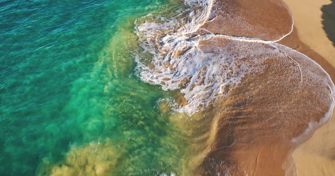 Aerial view flying over tropical white sand beach at sunrise