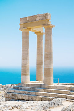Fototapeta Famous Greek temple three pillars against clear blue sky and sea in Lindos Acropolis Rhodes Athena Temple, Greece