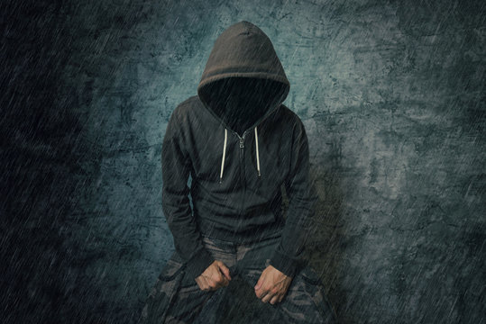 Spooky evil criminal person with hooded jacket in rain