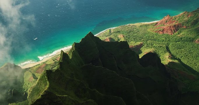 Aerial view flying over jungle mountain peaks revealing tropical coastline, Na Pali coast Kauai