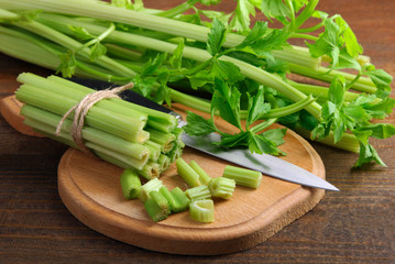 Fresh sliced green celery on wooden cutting Board on the brown wooden background